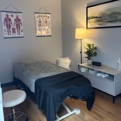 Cozy massage therapy room with anatomical charts and soft lighting.