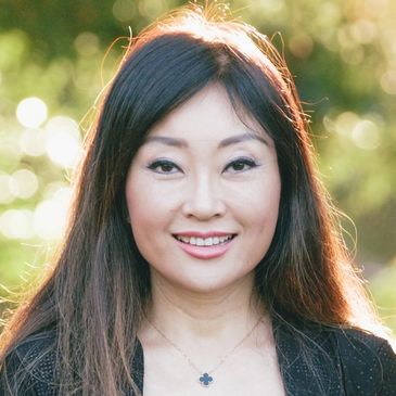 Smiling woman with long hair in natural outdoor setting.