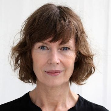Portrait of a woman with short wavy brown hair and blue eyes.