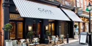Outdoor seating at a stylish cafe with a striped awning.