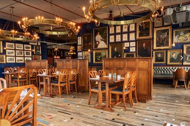 Cozy restaurant with wooden furniture and vintage portraits on the walls.