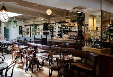 Cozy cafe interior with wooden chairs and tables under warm lighting.