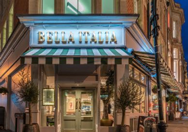 The entrance of Bella Italia restaurant at night with charming lighting.