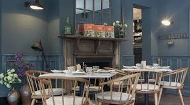 Cozy dining area with wooden chairs and a fireplace in a blue-toned room.