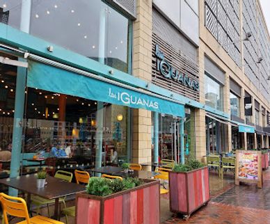 Exterior view of Las Iguanas restaurant with outdoor seating and teal awnings.