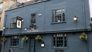 The exterior of The Bath House pub with hanging plants and dark blue paint.