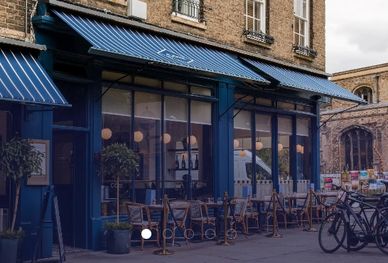 Cozy blue-themed café with outdoor seating and a bicycle parked nearby on a quiet street.