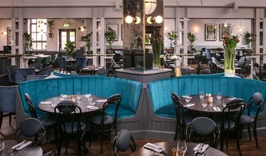 Elegant restaurant interior with teal booth seating and round tables.