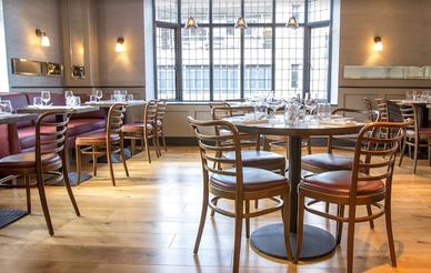 Elegant restaurant interior with wooden chairs and natural light from large windows.
