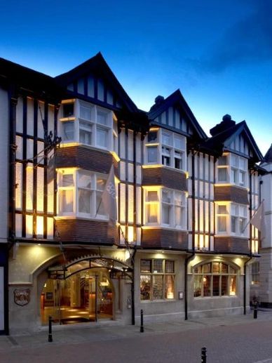 Historic Tudor-style building with warm lighting against a twilight sky.