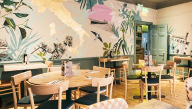 Cozy cafe interior with wooden chairs and tropical wall mural.