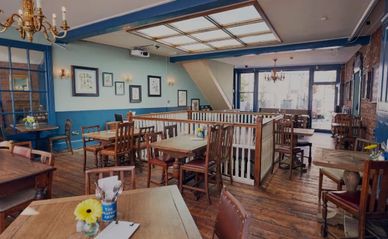 Cozy cafe interior with wooden tables, chairs, and blue walls.