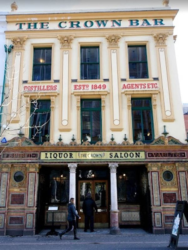 Historic facade of The Crown Bar with ornate detailing and people entering.