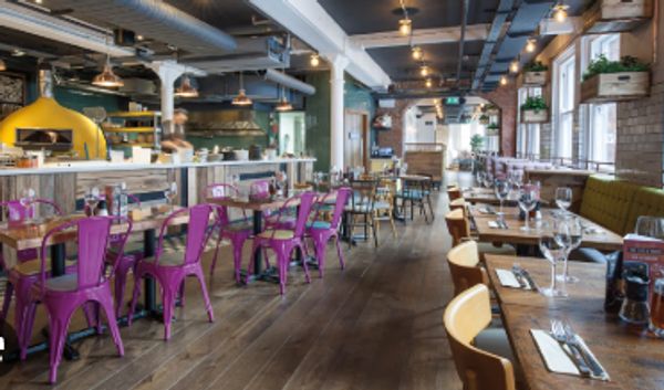 Modern restaurant interior with vibrant purple chairs and wooden tables.