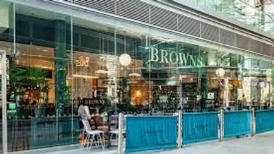 Modern cafe with glass walls and outdoor seating on a city street.