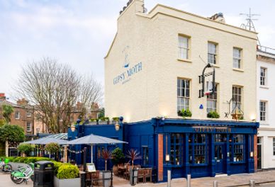 A charming traditional pub with outdoor seating on a street corner.
