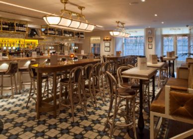 Cozy bar interior with wooden furniture and patterned tile floor.