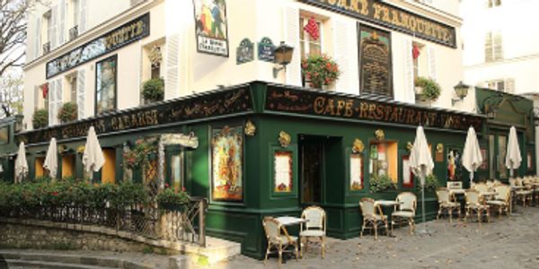 Charming Parisian café with outdoor seating and classic green facade.
