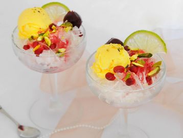 Two glasses of shaved ice dessert with mango ice cream and fruits.