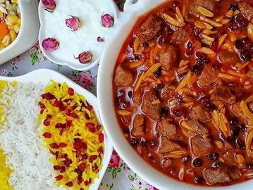 Traditional Persian meal with saffron rice, stewed meat, and yogurt with rose petals.