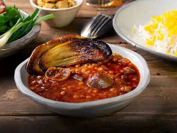 Persian stew with eggplant, mushrooms, and saffron rice on a wooden table.