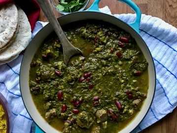 A pot of green stew with kidney beans, served with flatbread and yellow rice.
