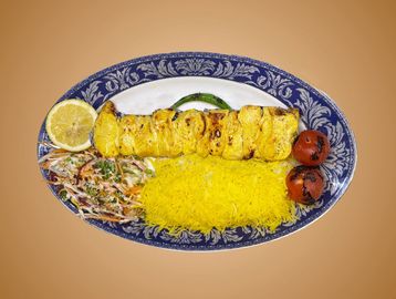 Grilled chicken kebab served with saffron rice, grilled tomatoes, and salad on a decorative plate.