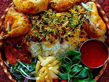 A vibrant platter of chicken biryani with sides and sauce on a decorative plate.