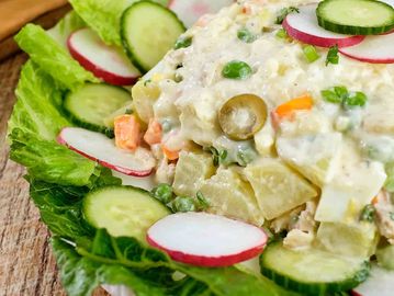 Creamy vegetable salad with peas, carrots, radishes, and cucumbers on lettuce.