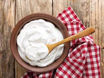 Creamy white yogurt in a wooden bowl with a spoon.