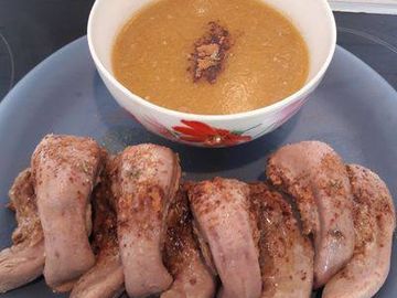 Plate of cooked chicken wings with a bowl of thick sauce.
