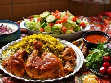 A vibrant meal with chicken, rice, fresh salad, and sauces on a colorful cloth.