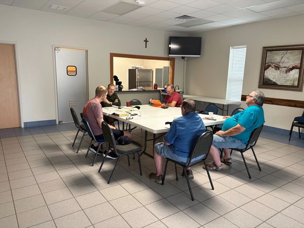 Group of men sitting around a table in a community room.