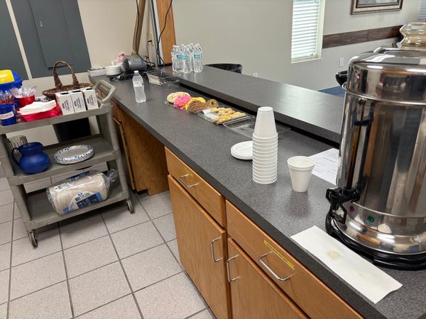 Refreshment area with coffee, cookies, and water bottles on a countertop.