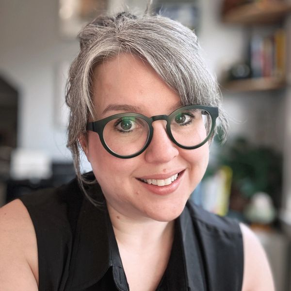 Smiling woman with glasses and gray hair.
