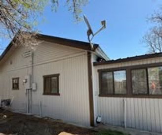 House with light siding, dark brown trim, multiple windows, and a satellite dish on the roof.