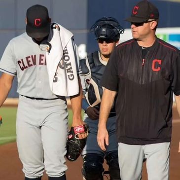 Cleveland baseball players and coach walking on field after game.