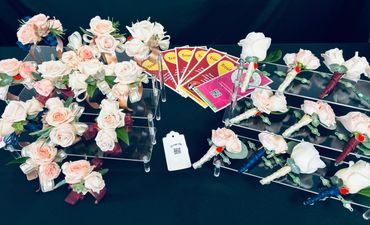 Elegant floral boutonnieres and wrist corsages displayed on clear stands.