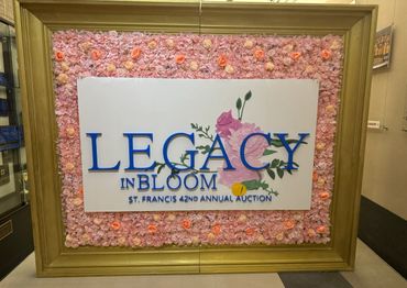 Sign for St. Francis 42nd Annual Auction with floral frame.