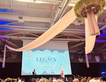 Elegant auction event with floral decor and a large presentation screen.