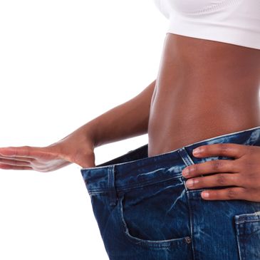 Woman pulling the front of her waistband of her pants away from her body showing significant weight