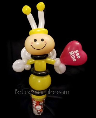 Cup of candy topped with a twisted balloon bee holding a heart. Holidays with special balloons.