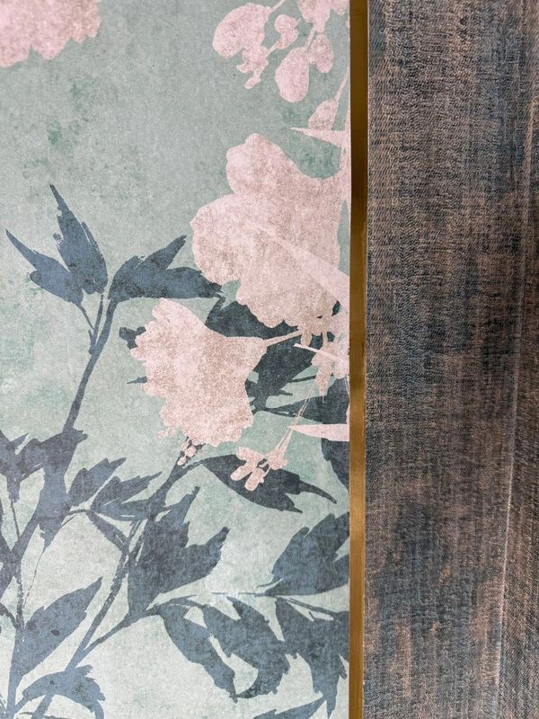 Floral wallpaper with pink flowers and blue leaves next to textured fabric.