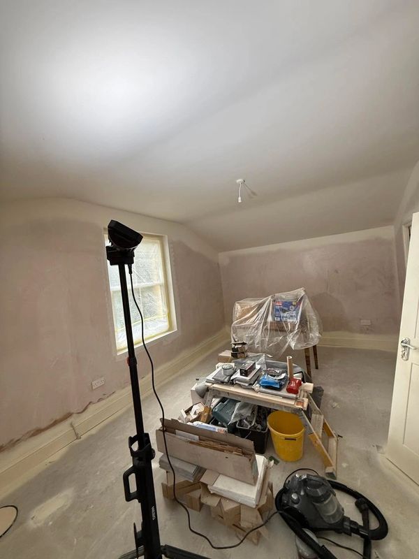 Room under renovation with tools and covered furniture.