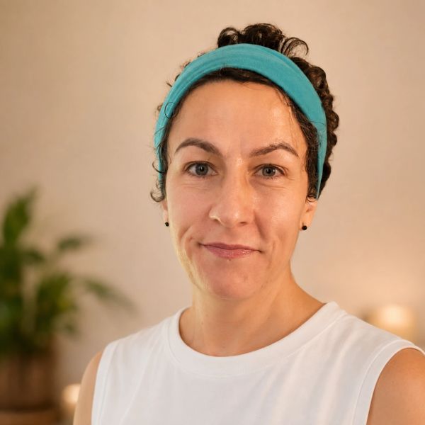 Woman with a teal headband smiling gently.