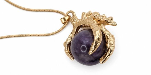 Gold pendant with claw holding a purple gemstone.