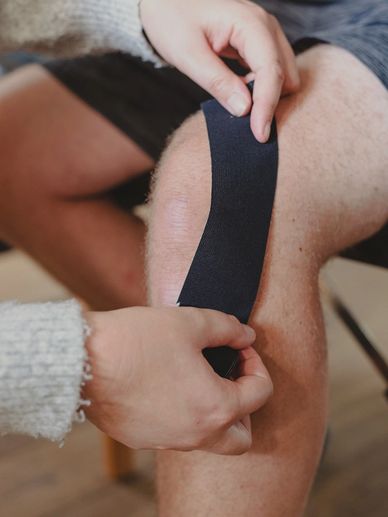 Chiropractor applying kinesiotape to patient's knee
