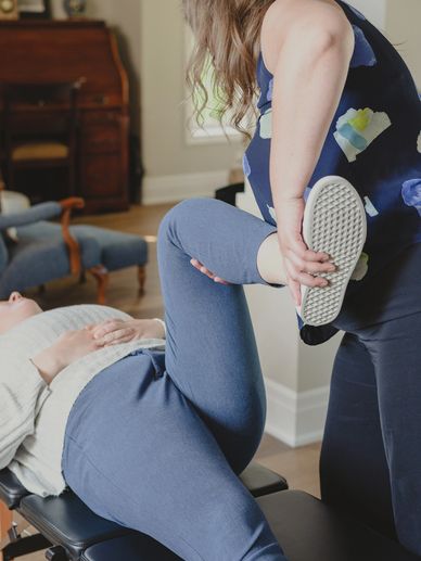 Dr. Kayla Rynne holding a patient's leg while she performs a stretch on her patient's hip