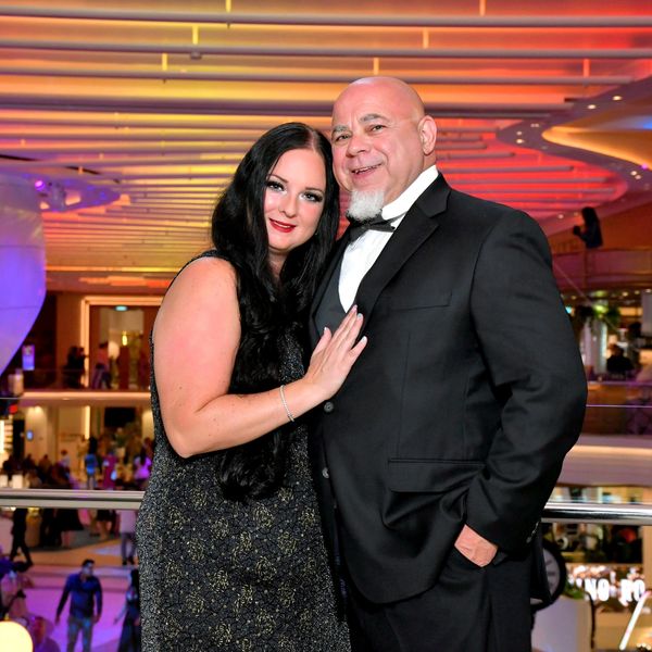 A couple dressed elegantly posing in a modern, colorful indoor setting.