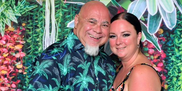 Smiling couple posing in front of a vibrant tropical backdrop.